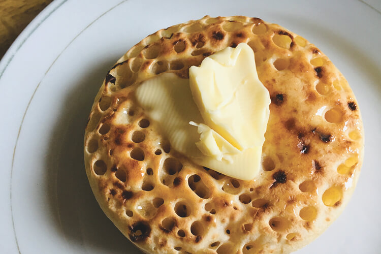 freshly toasted crumpet with butter on a plate